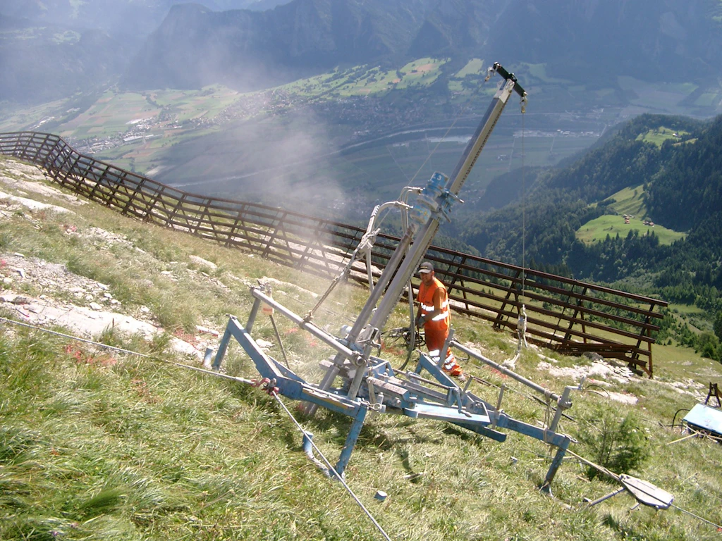 Lavori di perforazione per l'installazione di ancoraggi a cavo a spirale contro le valanghe di scorrimento.